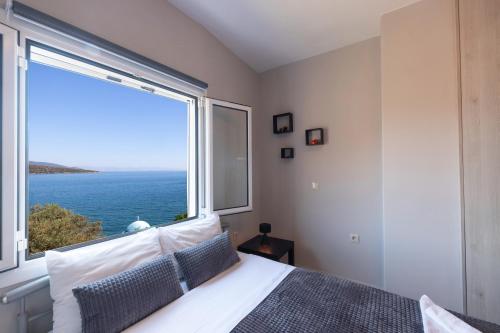 a bedroom with a large window overlooking the ocean at SAVINKA in Ancient Epidauros
