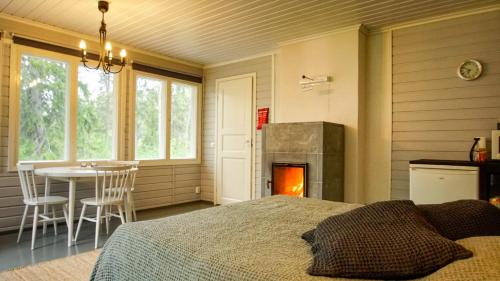 a bedroom with a bed and a table and a fireplace at Venejoen Piilo - Kuohu in Kontiolahti