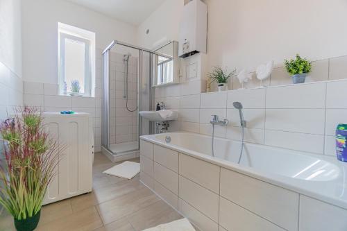 a white bathroom with a tub and a sink at Ostseeapartment_80m2_3xSchlafzimmer_2xParkplatz_Netflix_Waschtrockner in Cottbus