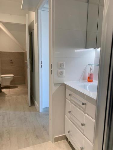 La salle de bains blanche est pourvue d'un lavabo et d'une salle de bains. dans l'établissement Blue bay studio terrasse, à Deauville