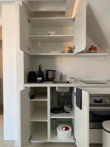 une cuisine blanche avec des étagères et des appareils blancs dans l'établissement Blue bay studio terrasse, à Deauville