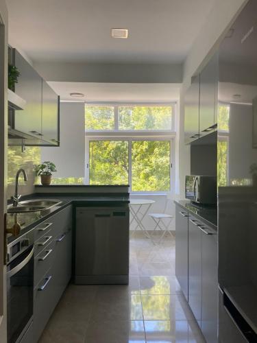 a kitchen with gray cabinets and a large window at Lisboa Central Apartment in Lisbon