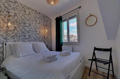 una camera da letto con un letto con lenzuola bianche e una finestra di Appartement "MEZZA" centre ville de VITRÉ a Vitré