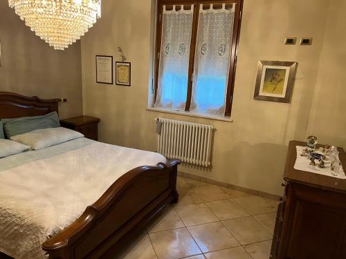 1 dormitorio con cama, ventana y lámpara de araña en Casa Margherita, en Mondovì
