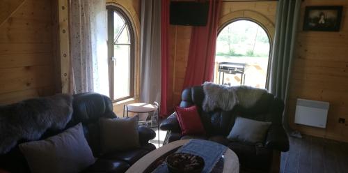 a living room with two couches and two windows at Woodorf drewnem usłane - domki z bala nad rzeką Słupią wśród pól i lasów z chatą grillową, ogniskiem i placami zabaw dla dzieci -Royal Red House z jacuzzi i ogrodzonym extra ogródkiem dla piesków, Royal Green House - bez jacuzzi in Ustka