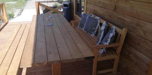 a wooden bench on a deck with a table at Woodorf drewnem usłane - domki z bala nad rzeką Słupią wśród pól i lasów z chatą grillową, ogniskiem i placami zabaw dla dzieci -Royal Red House z jacuzzi i ogrodzonym extra ogródkiem dla piesków, Royal Green House - bez jacuzzi in Ustka