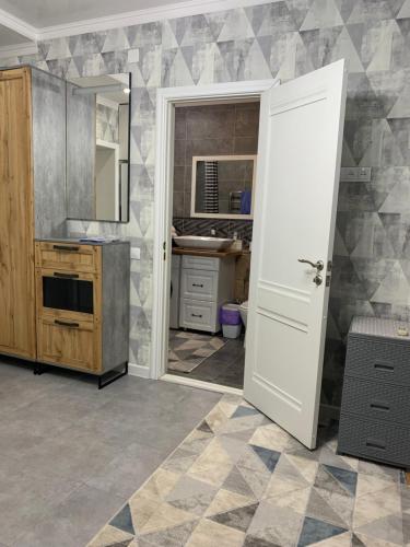 uma cozinha com um lavatório e uma porta branca em Loft Studio Apartment in Aktau em Aktau