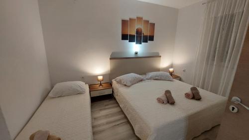 a bedroom with two beds with slippers on them at Apartments Pletikosa in Brodarica