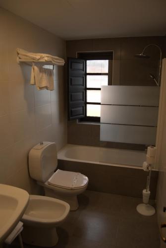 a bathroom with a toilet and a tub and a window at Hotel Palacio de los Vallados in Lastres
