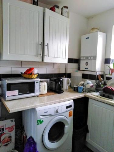 a kitchen with a microwave and a washing machine at Comfortable double bedroom in London in Hornchurch