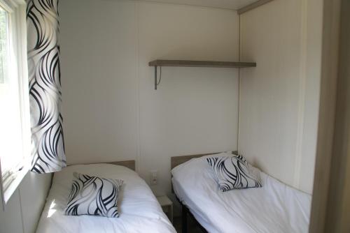 two beds in a small room with white walls at Les Roulottes & Cottages du Moulin in Chenillé-Changé