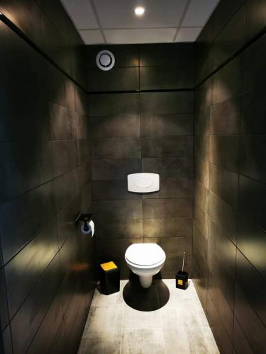 La salle de bains est pourvue de toilettes dans un mur noir. dans l'établissement Appartement Indépendant dans le Résid hôtel idéal pour les vacances - séminaires - déplacements pro 