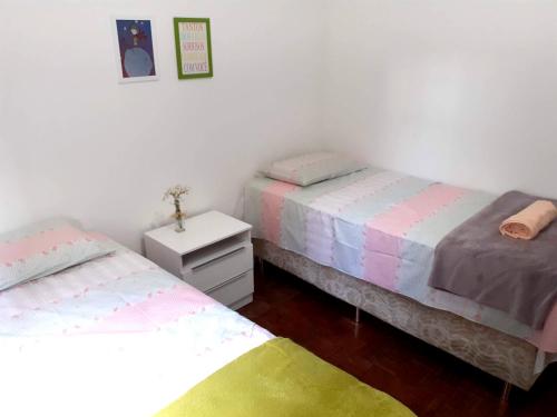 a room with two beds and a night stand with two beds at Lindo quarto na Praia de Botafogo in Rio de Janeiro