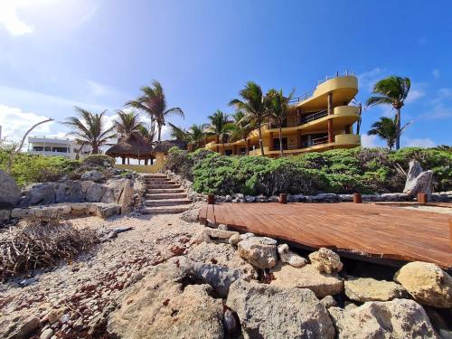 a resort on a rocky beach with palm trees at STYLISH OCEANFRONT CONDO with POOL in Mahahual