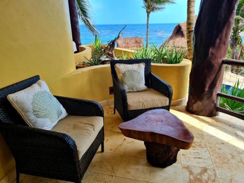 two chairs and a table on a balcony with the ocean at STYLISH OCEANFRONT CONDO with POOL in Mahahual