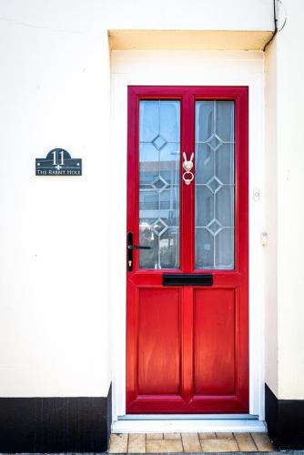a red door with a window on a building at Alice in Wonderland cottage by the sea in Torquay