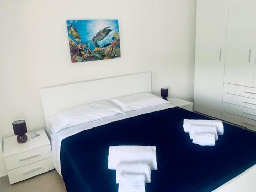 sypialnia z niebieskim łóżkiem i ręcznikami na nim w obiekcie koreMare w mieście Marina di Ragusa