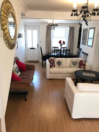 a living room with couches and a dining room at Alice in Wonderland cottage by the sea in Torquay