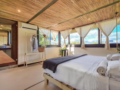 Un dormitorio con una cama grande y ventanas. en Suites Tulum, en Tulum