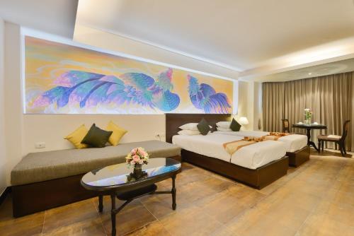 a hotel room with two beds and a painting on the wall at The Grand Sathorn in Bangkok