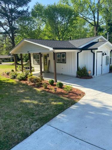 a small white house with a porch and a driveway at Cozy 2-bedroom Farmhouse with parking on premise in Smyrna
