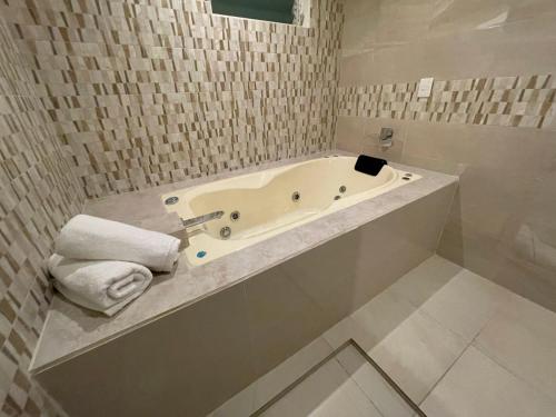 a bathroom with a bath tub with towels at ABERDEEN HOTEL DOLORES HIDALGO in Dolores Hidalgo