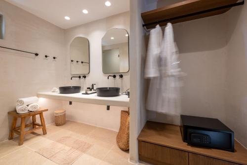 a bathroom with two sinks and a tv in it at Rocabella Mykonos Hotel in Agios Stefanos