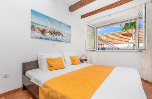 sypialnia z łóżkiem z pomarańczowymi poduszkami i oknem w obiekcie Apartman Daniela w mieście Sobra