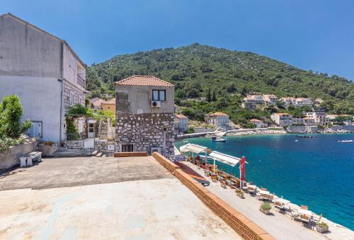 a building next to a body of water with a mountain at Apartments Daniela & Karlo in Sobra