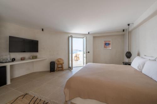 a bedroom with a large bed and a tv at Rocabella Mykonos Hotel in Agios Stefanos