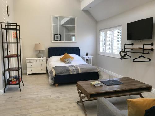 a bedroom with a bed and a living room with a table at Cosy cottage in the heart of the Cotswolds in Cirencester