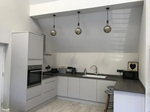a kitchen with white cabinets and stainless steel appliances at Cosy cottage in the heart of the Cotswolds in Cirencester