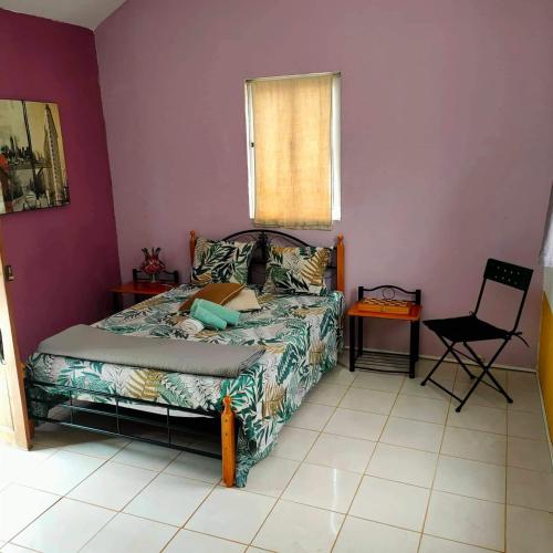 a bedroom with a bed and a chair and a window at gîte de rando haut in Mato Correia