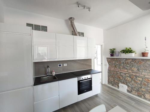 a kitchen with white cabinets and a sink and a fireplace at Openspace a pochi passi dal mare in Lerici