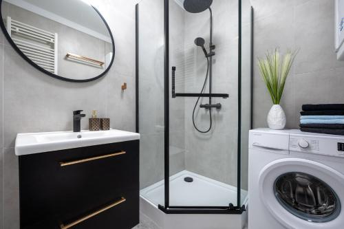 a bathroom with a shower and a washing machine at Apartament ALGA2 in Darłowo