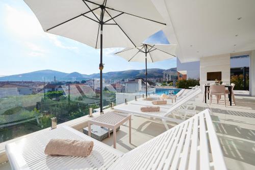 a patio with white tables and chairs and an umbrella at Villa Trogir 2 in Trogir