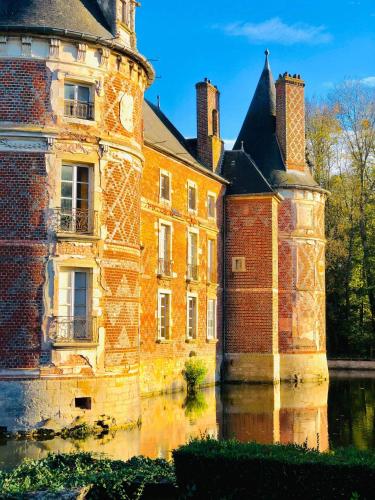 an old brick building with water in front of it at Guest-House Château de Longecourt en Plaine in Longecourt-en-Plaine