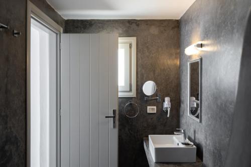 un bagno con un lavandino bianco e uno specchio di Hotel Goulielmos ad Akrotírion