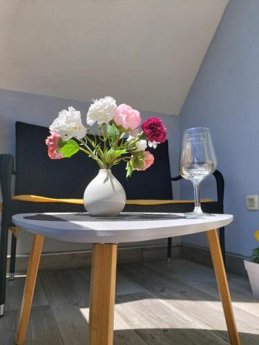 a vase of flowers on a table with a wine glass at Elegant Inn Gospić in Gospić