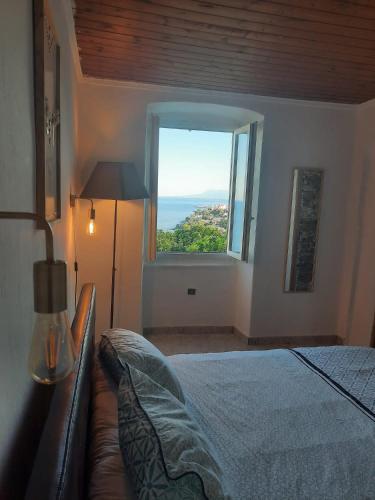 une chambre avec un lit et une grande fenêtre dans l'établissement pietranera village terrasse vue exceptionnelle sur la mer, à San-Martino-di-Lota