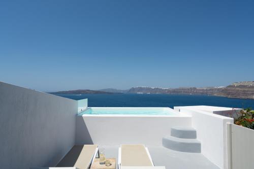 a white house with a swimming pool and the ocean at Hotel Goulielmos in Akrotiri