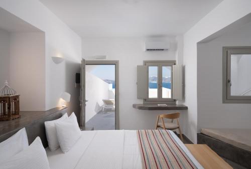 a white bedroom with a bed and a mirror at Hotel Goulielmos in Akrotiri