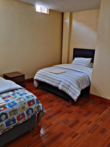 a bedroom with two beds and a wooden floor at La Ruta in Paracas