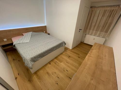 a small bedroom with a bed and a wooden floor at Delux apartment ARSO in Velenje