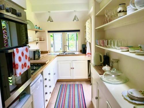a kitchen with white cabinets and a sink at Key Cottage, sleeps 8 in Brimscombe