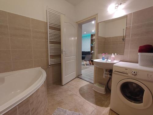 a bathroom with a tub and a sink and a washing machine at Family Residence in Eger