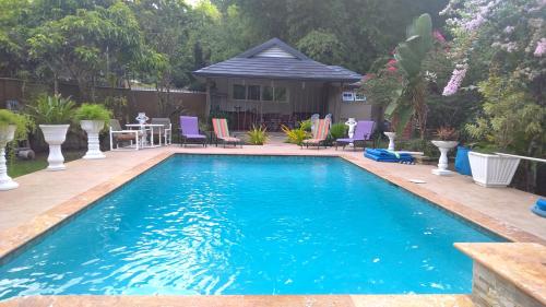 a swimming pool in a yard with chairs and a house at Vista Stays in Curepe