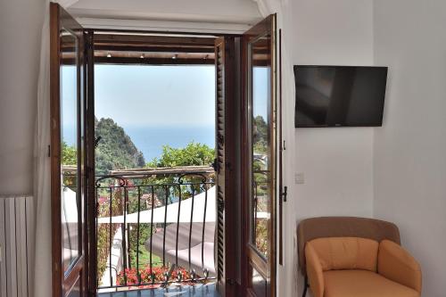 a room with a balcony with a television and a chair at Amalfi Sky View in Scala