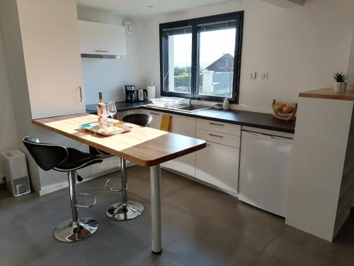 cocina con mesa de madera y 2 taburetes en les vignes en Villaz