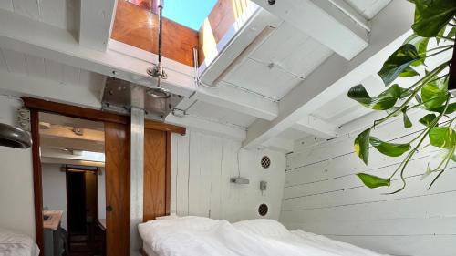 Unique Boat Accomodation - Bornholm في Hasle: غرفة نوم بجدران بيضاء وسرير بملاءات بيضاء